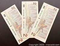 Reverse side of three $2 banknotes showing robins and CANADA text