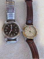 Two wristwatches side by side showing dials, cases and straps