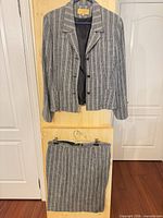 Full view of blazer and skirt hung on door showing matching set