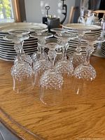 Group of nine upside-down Ancenis crystal wine glasses in front of stacked plates