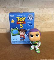 Buzz Lightyear figure standing beside original Toy Story 5 Mystery Minis box