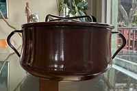 Side view of brown enamel casserole showing curved profile and side handles