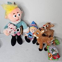 Group shot of all plush items: large Hermey holding elephant, small Hermey, two reindeer