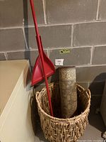 Rolled area rug runner, woven basket, broom and dustpan grouped together
