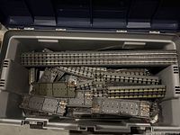Bin containing numerous gray roadbed O-gauge track pieces
