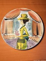 Full view of round handpainted plate showing woman and drapery scene