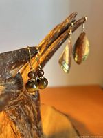 Both earring pairs on display; tiger’s eye pair foreground, mixed-metal pair background