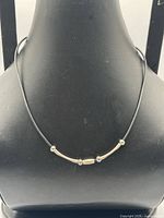 Necklace displayed on bust showing front tube and bead arrangement