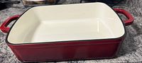 Front angled view of red enameled cast iron rectangular roaster showing interior and handles