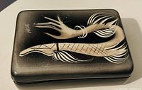Lid of trinket box showing signature and stylized motif