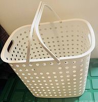 White perforated plastic laundry basket with two swing handles