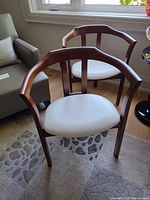 Front view of both chairs showing wood frames and white leather seats