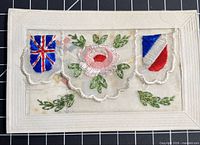 Front of embroidered silk postcard showing flags and rose motif