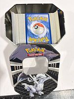 Open Reshiram tin filled with stacked Pokémon cards