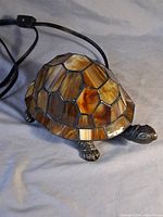 Side view of turtle lamp showing stained glass shell pattern, metal head and legs, power cord visible