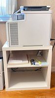Printer on stand with paper and pens visible