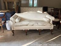 Front view of cream upholstered camelback settee showing overall design and legs