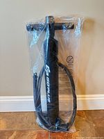 Front view of sealed black Goplus hand pump with hose attached