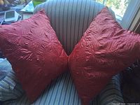 Two rust orange quilted satin pillows on striped chair