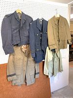 Four RCAF uniform sets hanging: two blue, two khaki, jackets with trousers