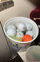 Plastic Becel bucket filled with assorted golf balls