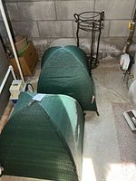 two green pop-up plant covers, metal plant stand in background