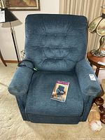 Front view of blue Pride power lift recliner with remote and brochure on seat