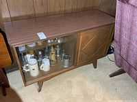 Front view of wooden server cabinet showing glass and wooden sliding doors, items inside for scale
