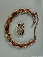 Necklace laid out with one screw-back earring visible