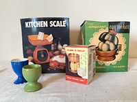 Group shot of boxed kitchen scale, egg cooker, egg cuber, and two egg cups