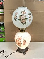 Full view of illuminated double-globe floral lamp showing both globes lit and base detail