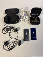 All items laid out: two iPods, Beats charging case with earbuds, Bose earbuds, zip Bose case, Apple cable