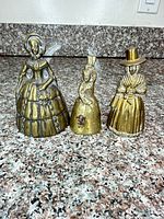 Group shot of three brass figurine bells
