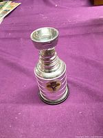 Full view of mini silver plated trophy on purple cloth