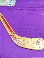 Full view of mini wooden Ottawa Senators hockey stick on purple background