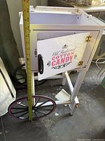 Full view of cotton candy cart stand showing wheels, door graphic, and measuring tape for height
