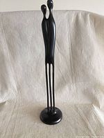 full front view of tall black resin couple sculpture on round base