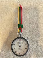 Front view showing dial, single button, lanyard and crest