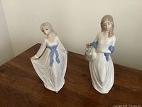 Front view of both porcelain figurines on wooden surface