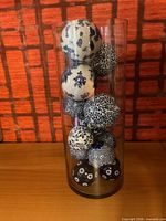 Full view of clear glass vase filled with blue and white porcelain balls