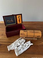Scroll on stand, open wooden box showing interior compartments with magnifier and gloves