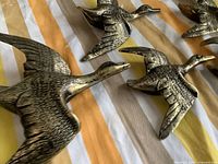 Close-up of three brass geese figures showing texture and finish