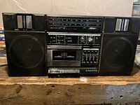 Front view of Sanyo boombox showing speakers, tuner scale, control panel, cassette deck and tape keys