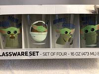 Front view of boxed set showing four Grogu glasses and captions