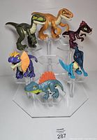 Front view of six Imaginext Jurassic World dinosaur figures on clear stand