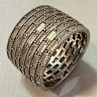 Angled view of the sterling silver wide band ring showing brick pattern and inner lattice