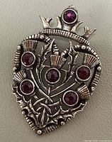 Front view of silver-tone Luckenbooth brooch with six purple stones and crown