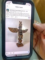 Front view of carved cedar totem pole on phone screen