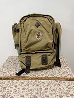 Front view of tan Camp Trails backpack on table