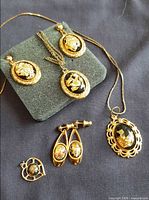 All jewellery pieces laid out: pendant with chain, matching stud earrings, drop earrings, scalloped pendant, small openwork pendant
